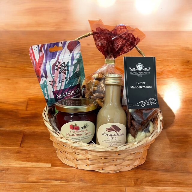 Geschenkkorb mit regionalen Produkten, darunter Gläser, Seifen und verpackte Spezialitäten auf Holztisch.
